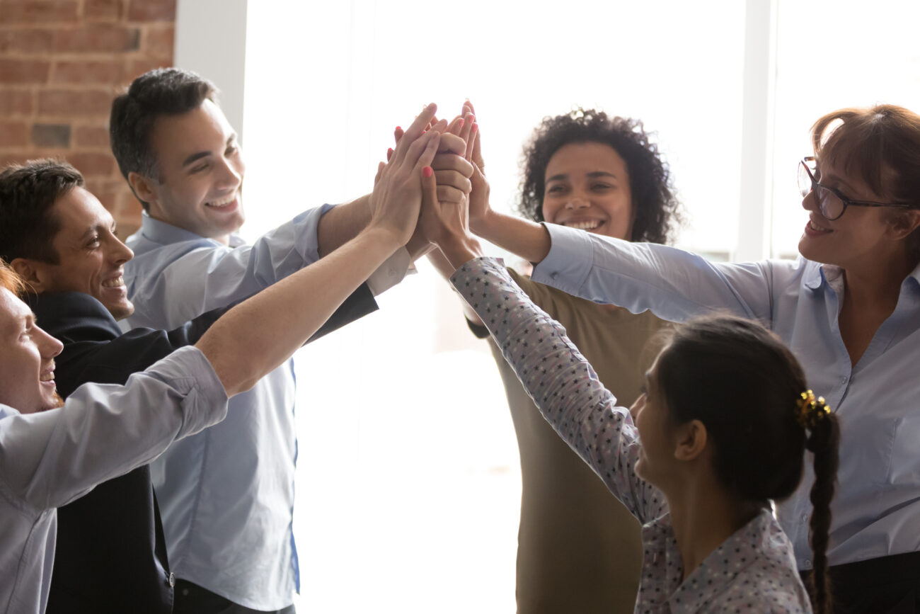 Overjoyed multi racial businesspeople succeed goal giving high five feels excited. Successful corporate team congratulating each other with victory achievement hold hands together show spirit of unity